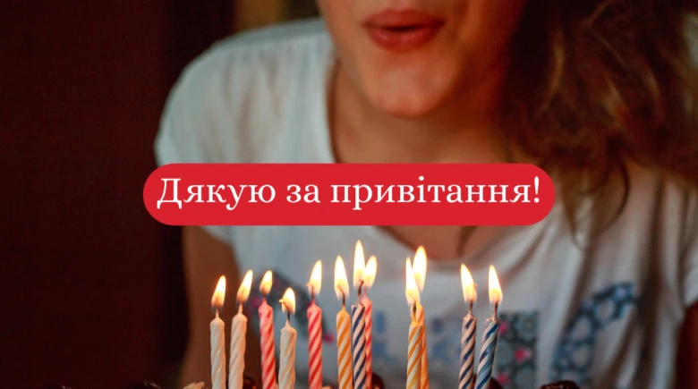 Чоловік дмухає свічки на торт з українським привітанням