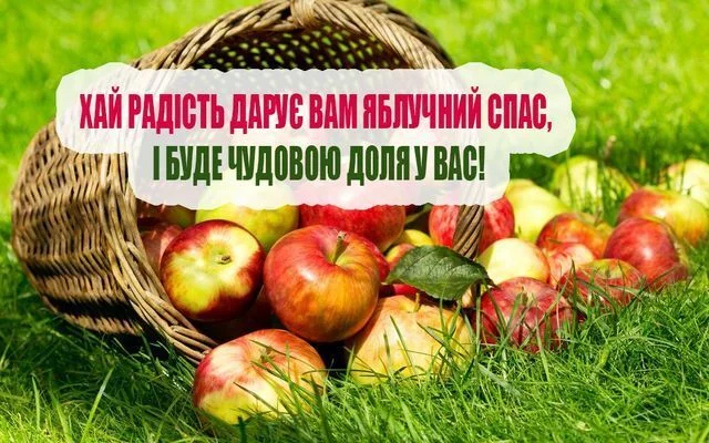 Корзина з яблук на траві та привітання до Яблучного Спасу.